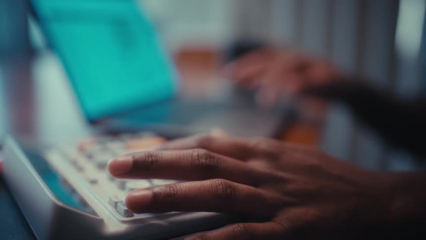 A persons fingers type on a laptop while the other hand taps a calculator beside it working through tasks with steady focus