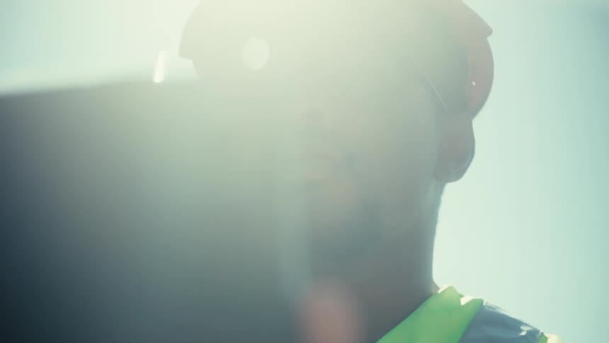 A construction worker in a hard hat looks at a tablet with the focus shifting from his face to the devices camera