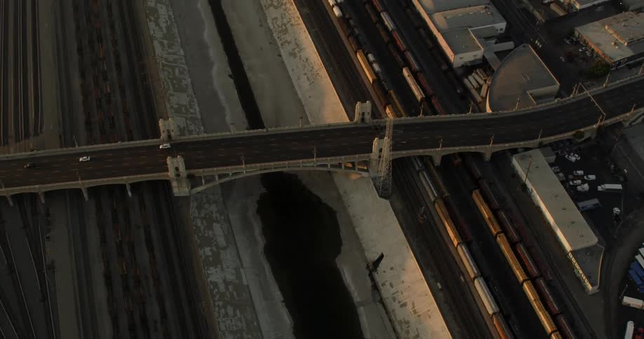 Cars driving over Los Angeles River Bridge at sunset