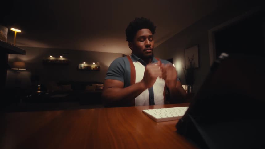 A man sitting in a room typing on a keyboard