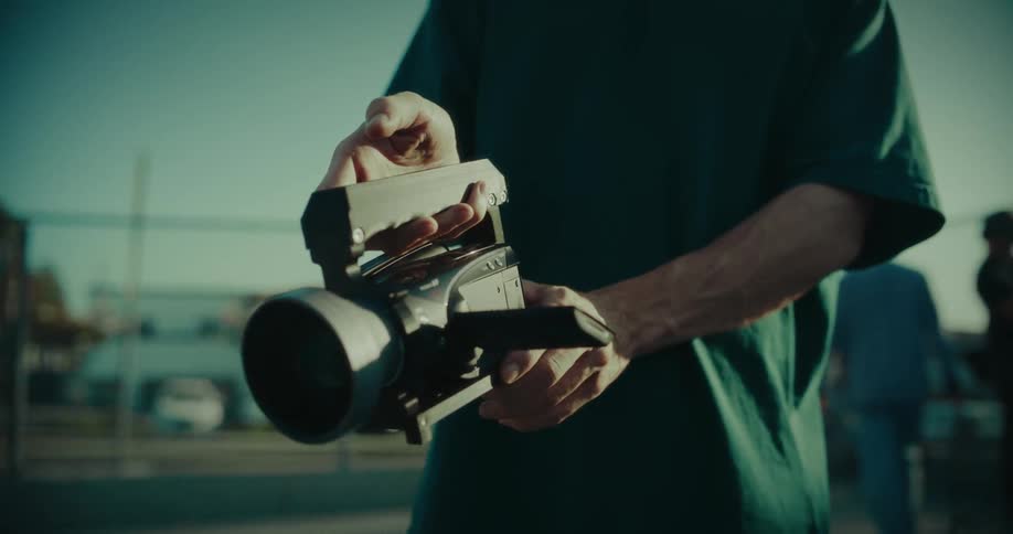 Close up of a young man using a camcorder while standing outdoors in a suburban city during daytime