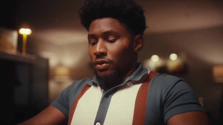 Young adult black man putting away a tablet computer and puffing with a tired and bored facial expression indoors during night time