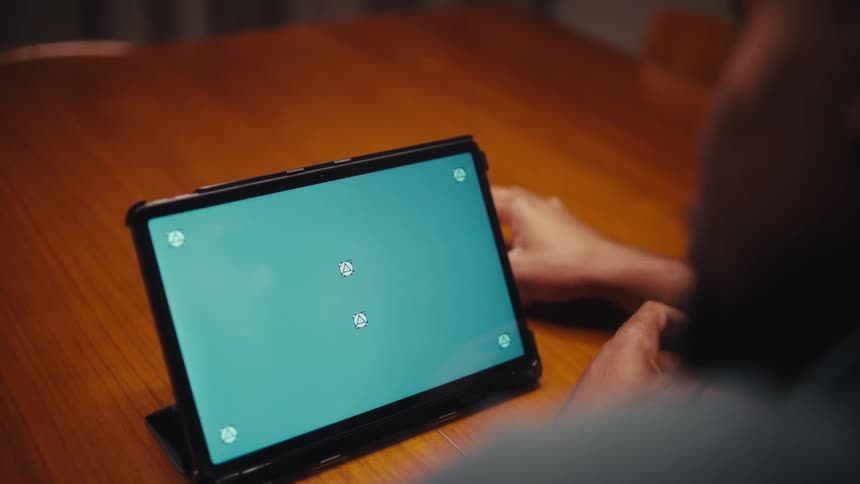Close up of a young black man using a tablet computer while sitting at a table indoors at night
