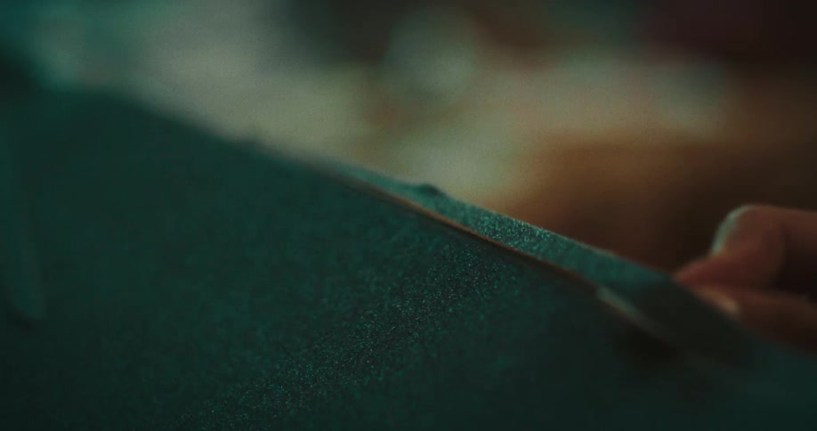 Hand of a black person cutting a piece of fabric with a blade indoors during day time