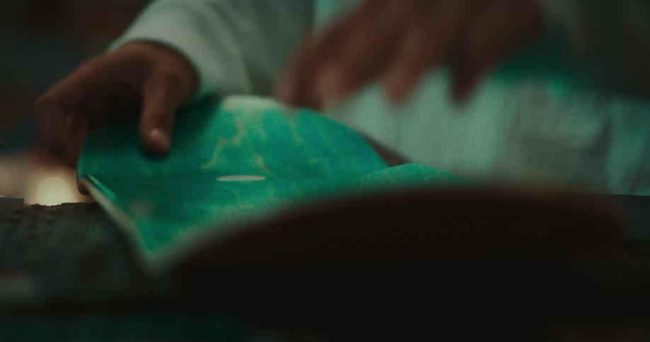 Adult male standing up indoors and removing plastic wrap from a skateboard