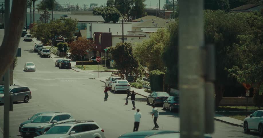 A group of young male friends skateboarding outdoors on a street in a suburban city during daytime
