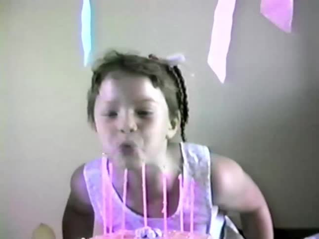 A child blowing out candles on a cake