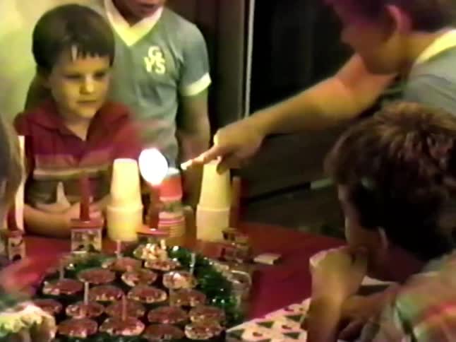 Mother and son exchange smiles after the boy blows out his birthday candles at a party