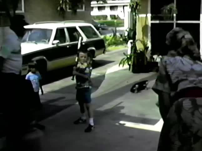 A family playing baseball in a driveway