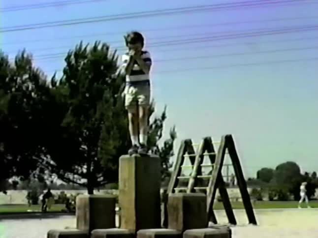 The boy jumps down into the sand in the playground