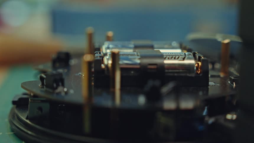 A macro shot reveals the internal hardware of an electronic device focusing on two lithium batteries installed on a black circuit board alongside several vertical copper pins and mounting components