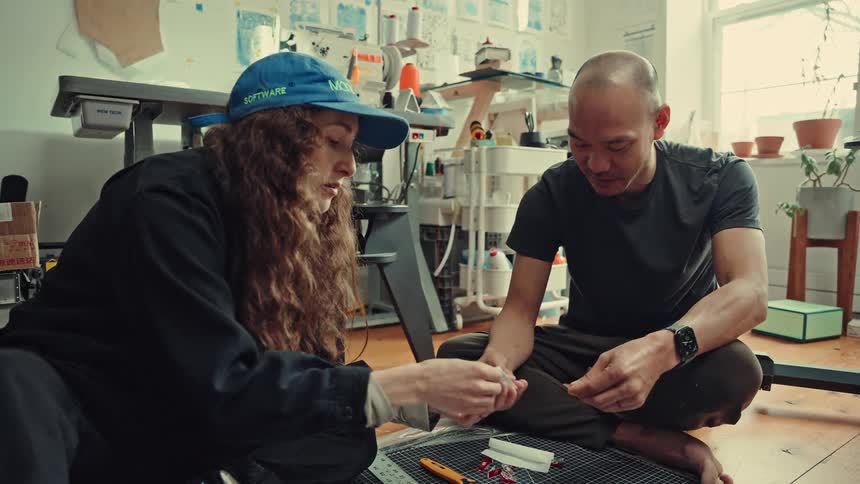 Man and a woman sit on the floor talking in a craft room during the daytime