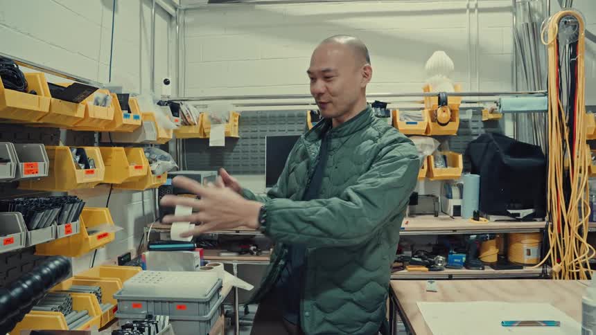 Man inside a factory is gesturing happily with his hands