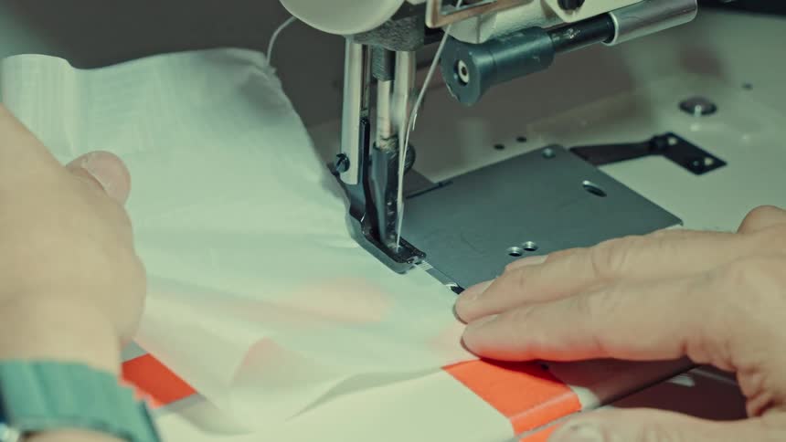 Male hands operating a sewing machine indoors