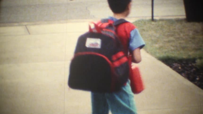 Two kids stand at midday holding their lunch boxes and wearing backpacks ready to head off to school with bright eager energy