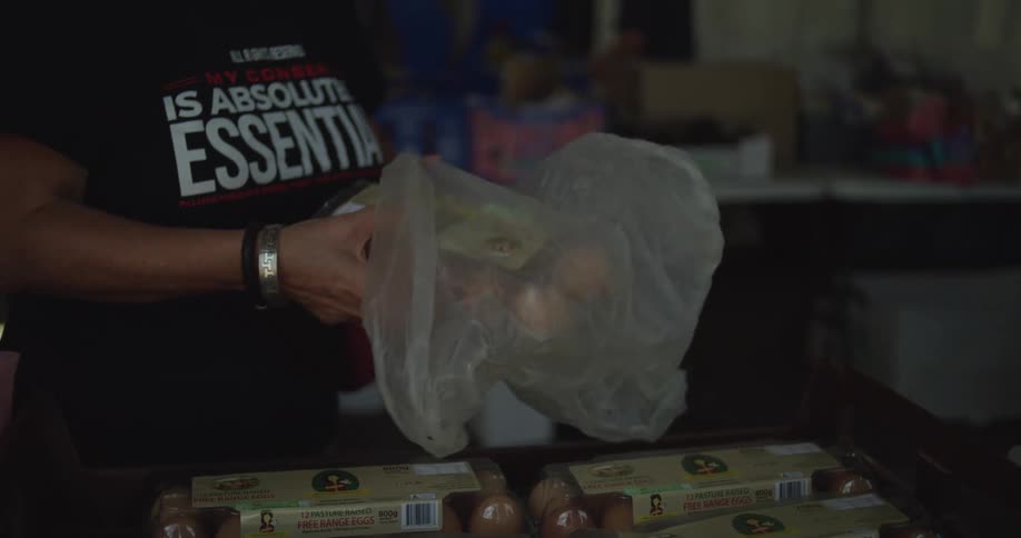 The woman puts eggs in a plastic bag