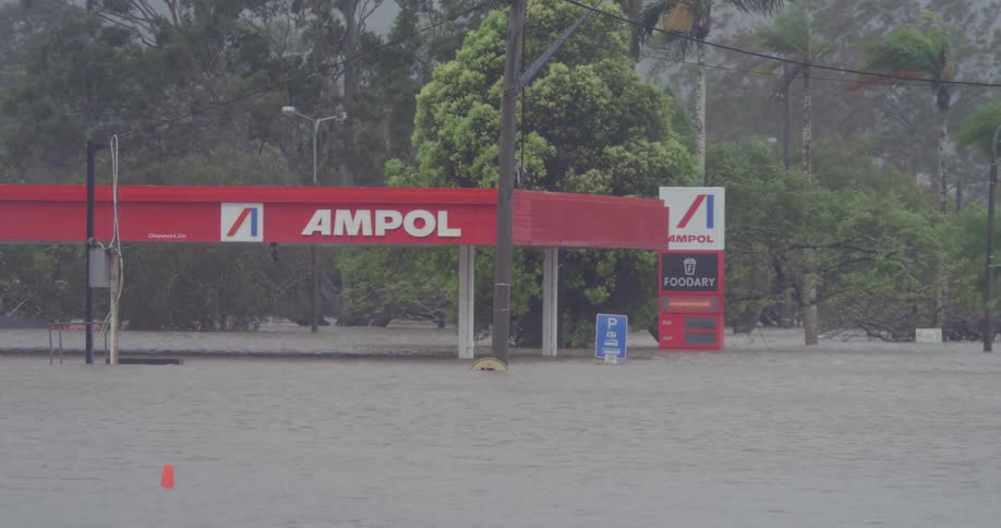 Flooded gas station next to an area with many trees outdoors during day time