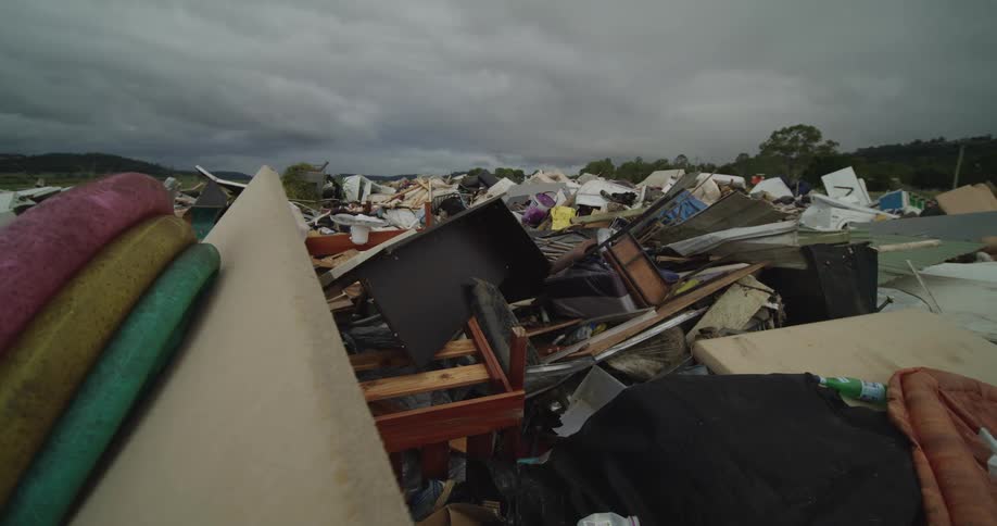 Video massive mound of destroyed furniture and household waste including mattresses sits in a large pile under a dark cloudy sky