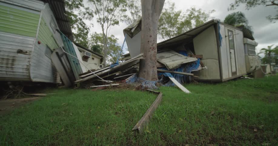 Broken pieces of wood surrounded by broken houses on a suburban area outdoors during day time