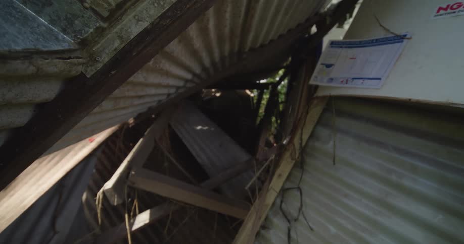 Collapsed corrugated metal structure with exposed wooden beams in outdoor setting