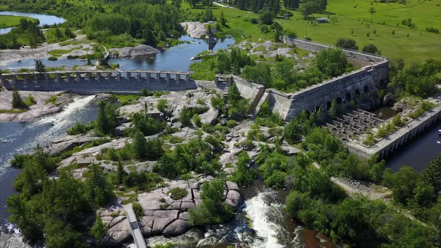 Water flowing through dam surrounded by green grass and trees