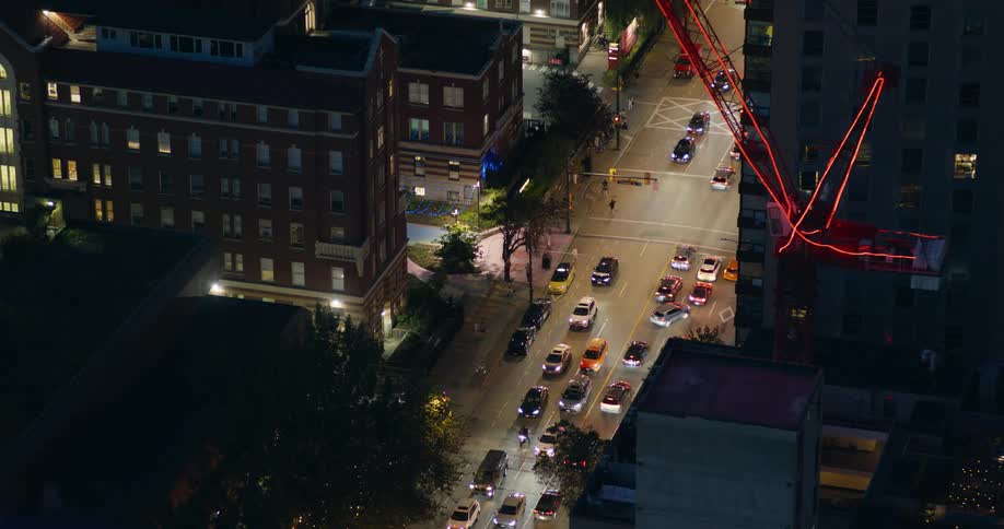 A busy city street at night filled with steady streams of cars moving through heavy traffic as tall highrise buildings tower on both sides