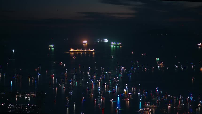 Lights are flashing on the boats in the water at night