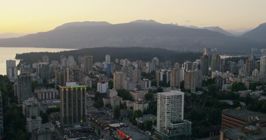 A city skyline at midday featuring a series of skyscrapers and highrise buildings with a mountain range in the background