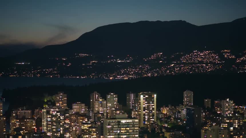 Neighborhood on a metropolitan area next to the coast with a mountain on the background and flickering red lights all over the city outdoors during dusk or dawn