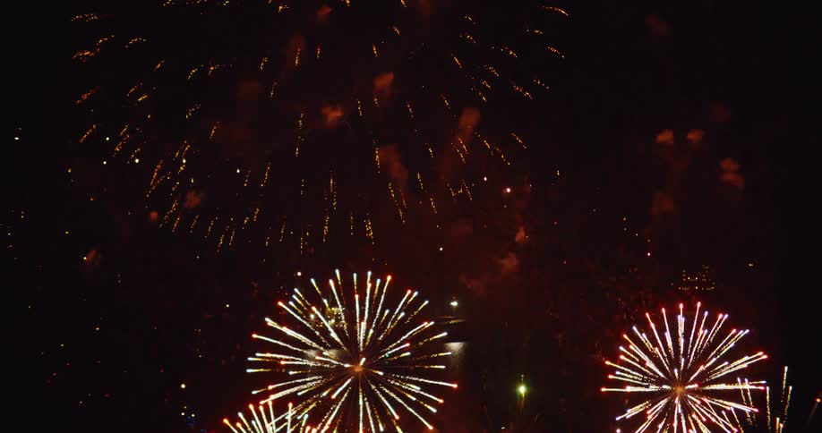 Boats sailing as colorful fireworks explode and glow over the water