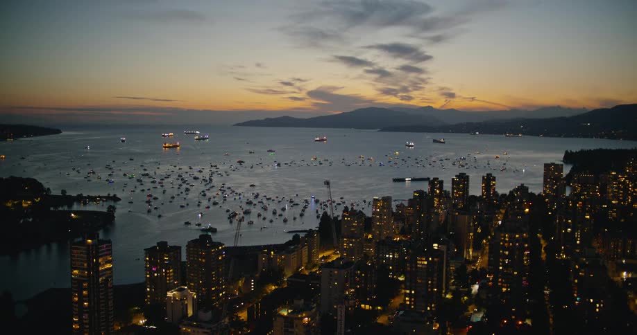 Aerial of boats anchored in a harbor beside a coastal metropolis