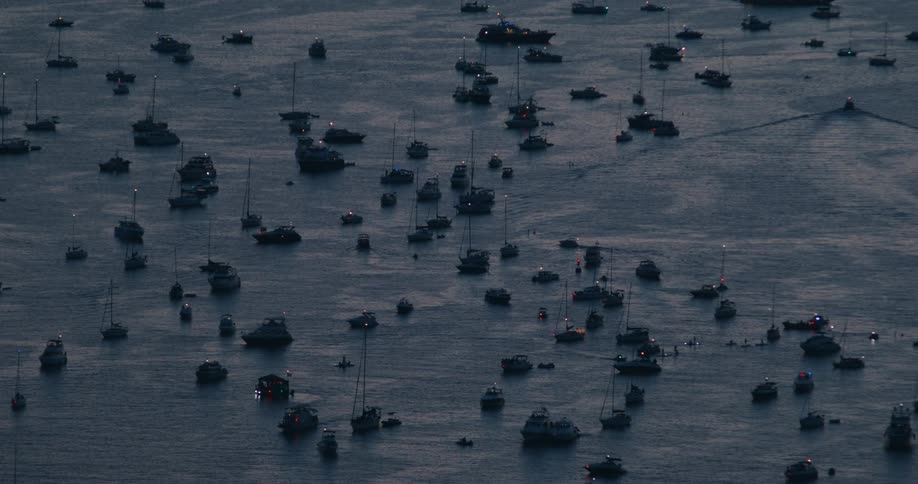 There are many large and smaller boats out in the water with their lights on