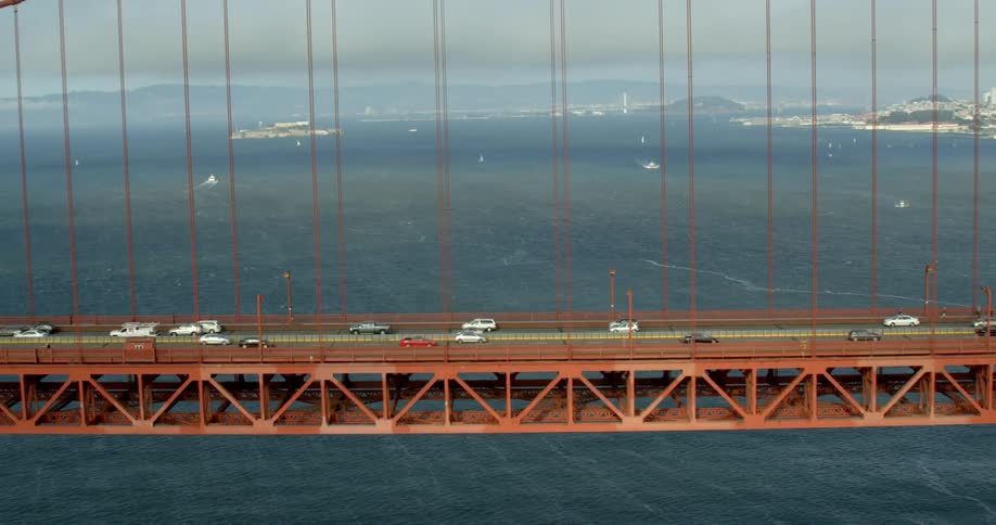 Cars cross Golden Gate Bridge with Alcatraz and San Francisco in the background