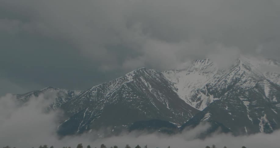 A snow capped mountain range outside a field