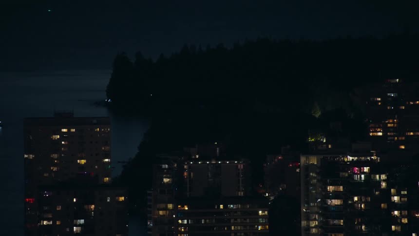 Several tall buildings with illuminated windows are visible at night