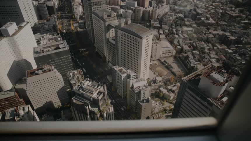 Through the tall buildings window traffic is flowing on the road