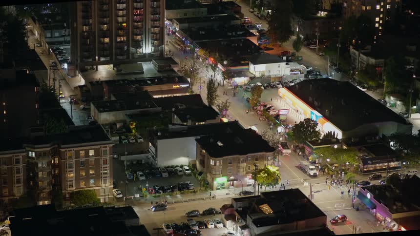 A high angle view of a city at an intersection with a police vehicle with flashing lights directing crowds of people in the street