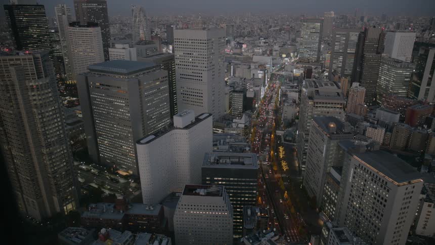 Traffic on a street surrounded by high rise buildings and skyscrapers on a metropolitan area outdoors during dusk or dawn