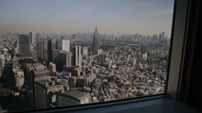 A city skyline seen from a skyscraper window with rows of highrise buildings and towering skyscrapers surrounding the city in every direction