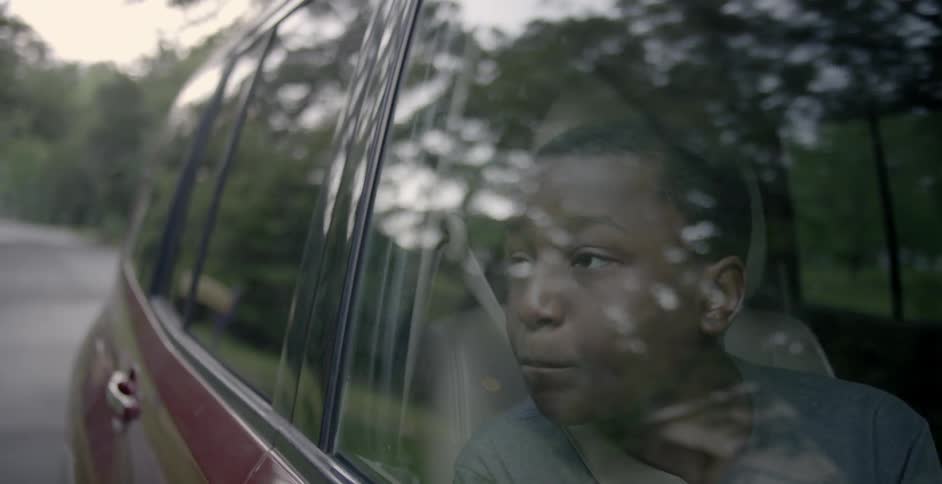 A boy looks out the window of a car