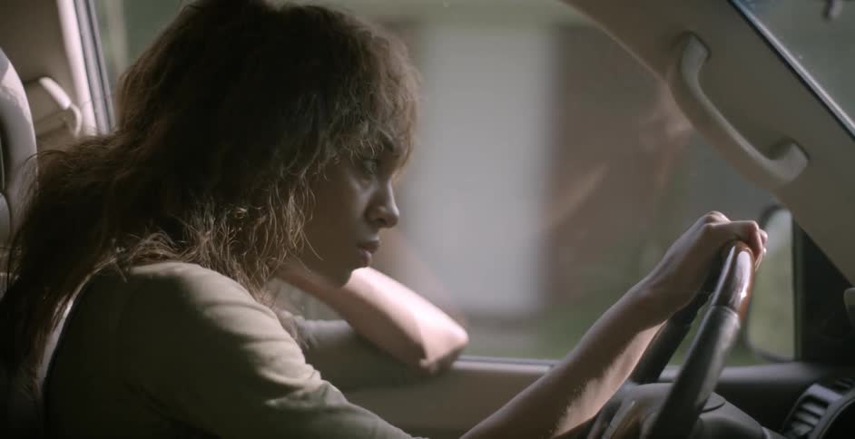A woman drives a car down a neighborhood street
