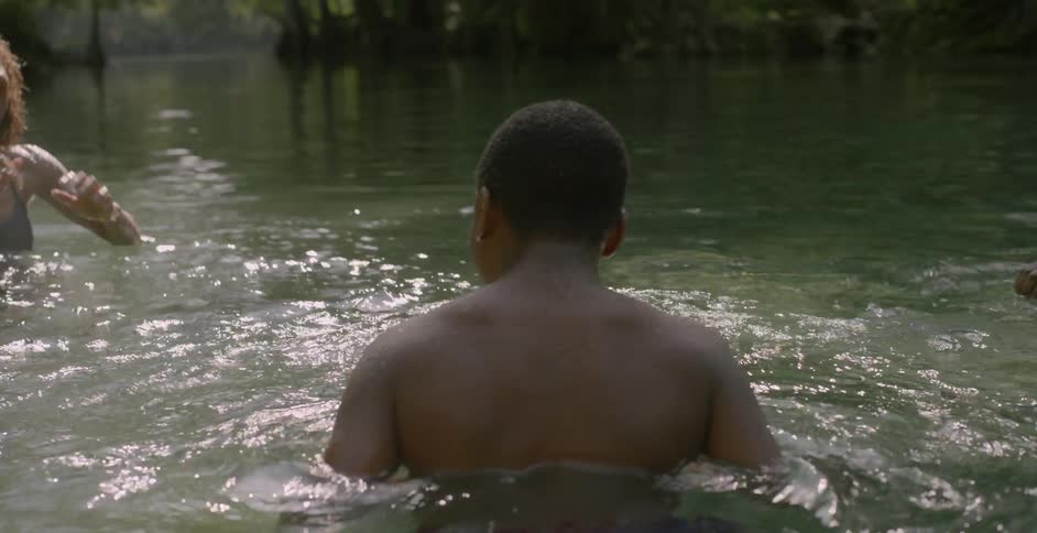A young man and woman in a body of water splash each other