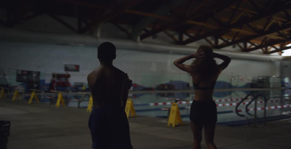 Two people walking toward an indoor lap pool