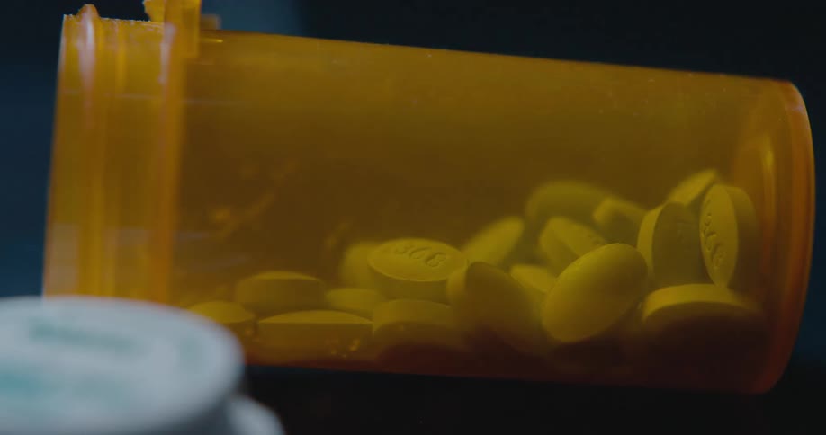 Blue pills inside an orange plastic bottle indoors
