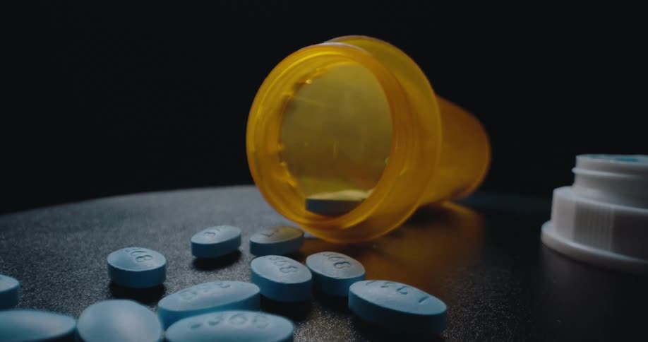 Medicine bottle that had fallen over and was open revealed with blue pills scattered throughout