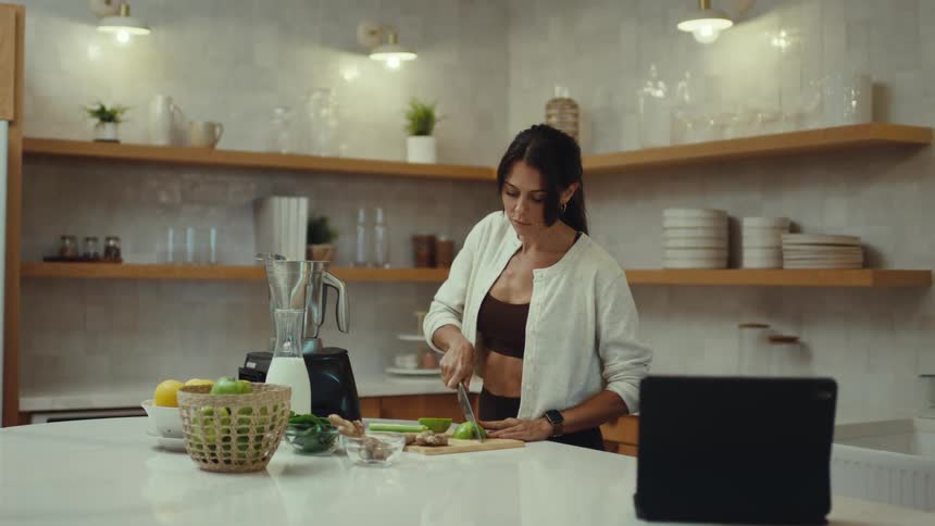 The woman is cutting up food in the kitchen