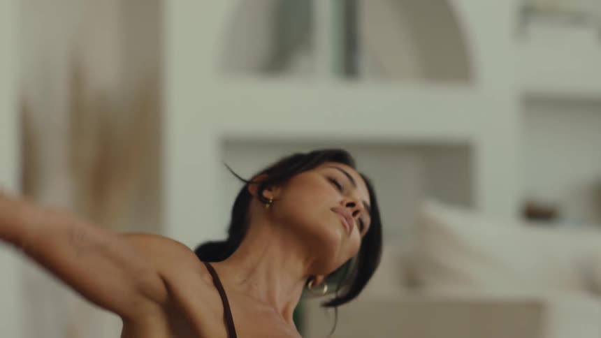 A close view shows the torso and legs of a woman in black athletic wear kneeling on a mat with a small tattoo visible on her arm