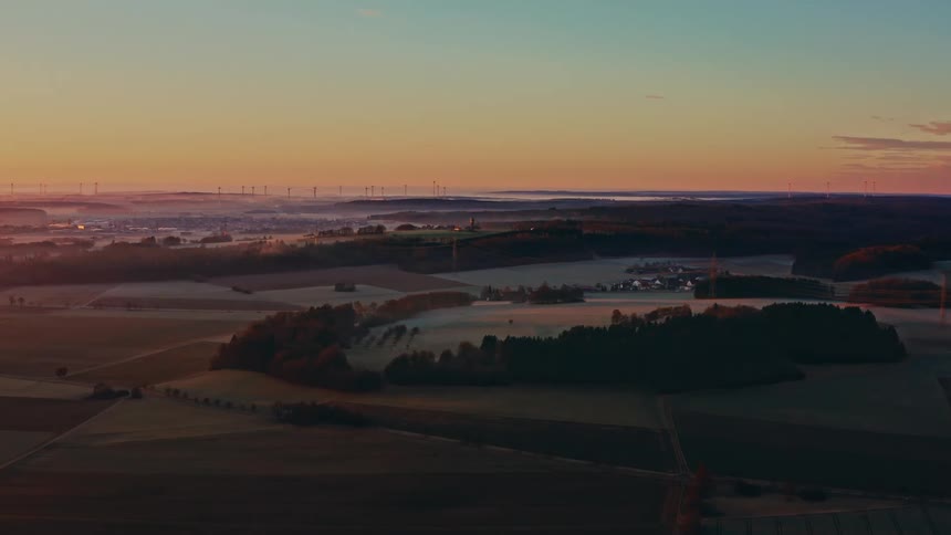 Aerial view of a peaceful rural landscape with fields and forests under the warm light of sunrise
