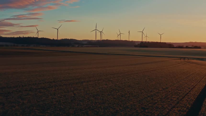 Wind turbines in agricultural field at sunset