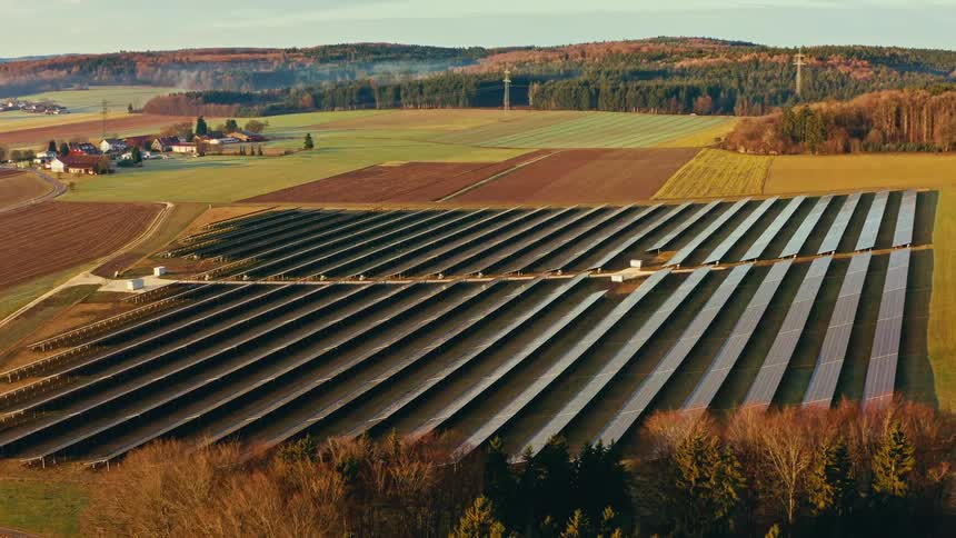 Field with rows of solar panels installed across agricultural land